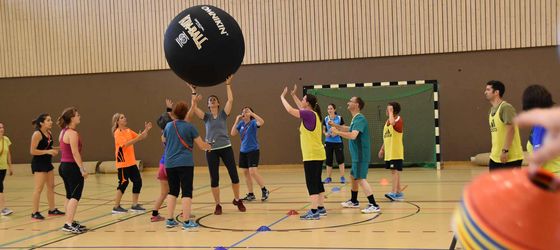 Eine Gruppe junger Leute spielt in der Turnhalle Kin-Ball